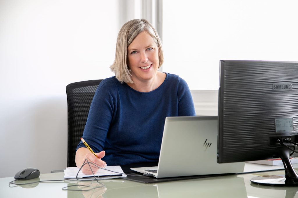 Jacqueline Widmer working at an office desk and looking at the camera