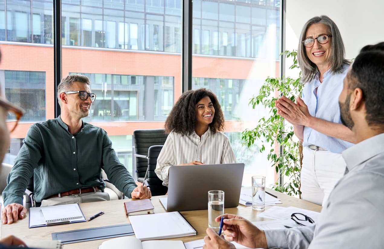 mature woman standing and addressing a group of people in an office meeting